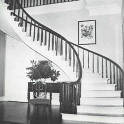 S-shaped stairs, nightstand with chair at the base of the stairs and a wall with a picture