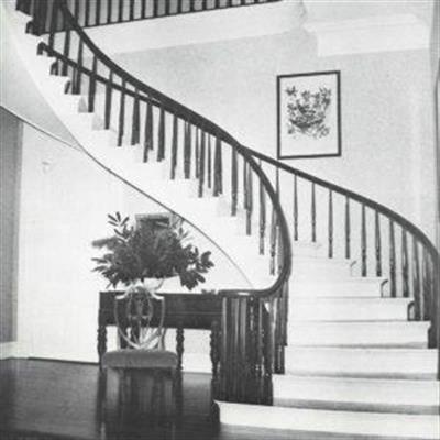 S-shaped stairs, nightstand with chair at the base of the stairs and a wall with a picture